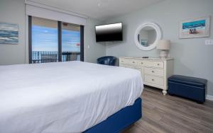 una camera da letto con un grande letto bianco e una televisione di Phoenix VI 6803 condo a Orange Beach Altre 42 foto
