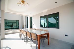 a dining room with a wooden table and chairs at The Woofington Pet Friendly Pool Villa in Ban Bo Prakhon