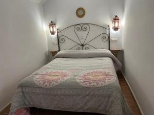 a bed in a bedroom with two lights on the wall at Cueva Abuelo Juan in Guadix