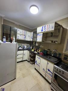 a kitchen with white appliances and a refrigerator at المنصوره الجديده جنه 2 شقه فيو فيلل وجاردن in Zayyān