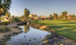 a golf course with a pond in front of a yard at Desert Springs award-winning Golf Resort apartment in La Hoya del Camaino