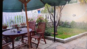 a table and chairs under an umbrella in a yard at Aegina Breeze House in Aegina Town