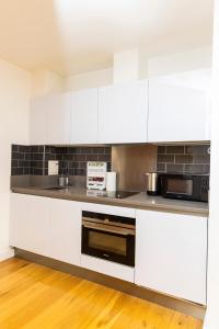 une cuisine avec des armoires blanches et un micro-ondes dans l'établissement Peninsula Life- Stylish Greenwich 1bed Flat, à Londres