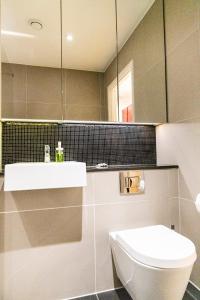 une salle de bain avec toilettes, lavabo et miroir dans l'établissement Peninsula Life- Stylish Greenwich 1bed Flat, à Londres 24 autres photos