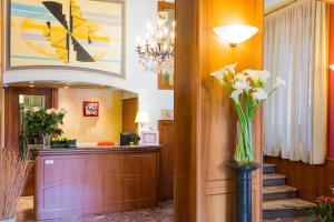 a lobby with a reception desk and a vase of flowers at Hotel Londra in Alessandria