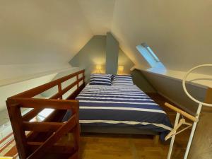 a bedroom with a bed with blue and white stripes at Appartement Ô Nid Perché Vue mer in Agon Coutainville