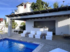 a patio with white chairs and a swimming pool at Front Beach Punta Rucia Villa in Punta Rucia