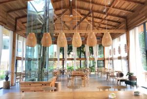 a large room with tables and chairs and windows at Yingde YeDuGu Resort in Gaozhoupu