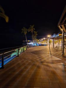 a boardwalk with palm trees and the ocean at night at Balcón de Puerto Naos in Los Llanos de Aridane