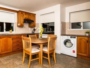cocina con mesa, sillas y lavadora en The Farmstead, en Drumfin