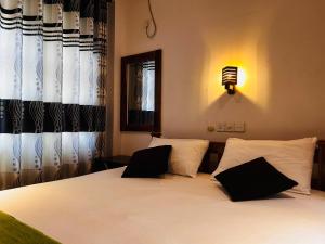 a bedroom with a bed with black and white pillows at Pearl Bungalow Trincomalee in Trincomalee