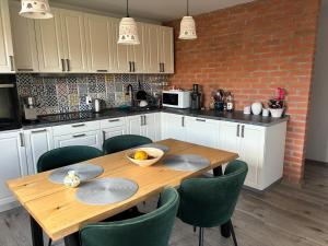 a kitchen with a wooden table and green chairs at Village house & Micro Winery in Sîntioana de Mureş +11 photos