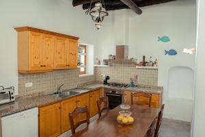 a kitchen with wooden cabinets and a table with fruit on it at Casa Mariposa Benirras in Sant Miquel de Balansat