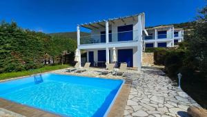 a villa with a swimming pool in front of a house at Amarandos Villas in Marantochori