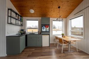 a kitchen with a table and a wooden ceiling at Smáratún Cottages & Chalets in Hellisholar