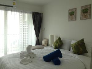 a bedroom with a white bed with a blue object on it at Ratchy Condo in Bang Sare