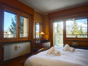 - une chambre avec un grand lit blanc et des fenêtres dans l'établissement Hostdomus - Good Vibes Apartment, à Sestrières