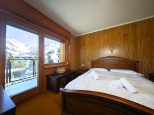 une chambre avec un lit et une grande fenêtre dans l'établissement Hostdomus - Good Vibes Apartment, à Sestrières
