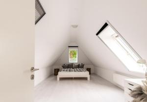 Dormitorio blanco en el ático con cama y ventana en Carpe Deimern in der Lüneburger Heide, en Soltau