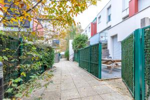 a fence with a sidewalk in front of a building at Triplex cosy à 20min des Champs Elysées in Gennevilliers