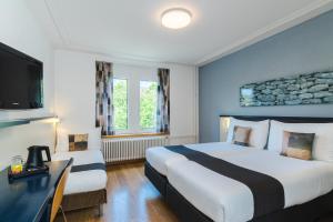 una camera d'albergo con due letti e una televisione di Hotel Bristol Zurich a Zurigo
