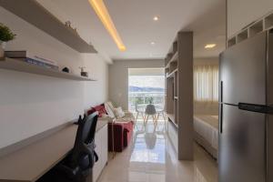 a kitchen with a refrigerator and a living room at Sweet Studio - GRU 19º in Guarulhos