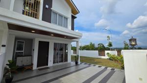 ein weißes Haus mit einer Veranda und einem Zaun in der Unterkunft Villa 63 3Bedroom 8pax in Beranang