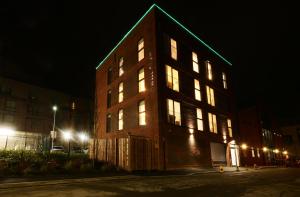 a large brick building with a green roof at night at Swift Apartments York in York