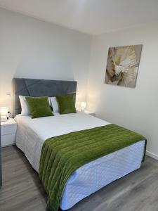 a bedroom with a large bed with a green blanket at Stay Lombinho in Porto da Cruz