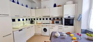 a kitchen with white cabinets and a table with food on it at Charmante Maison de village avec étage in La Couarde-sur-Mer +1 photo