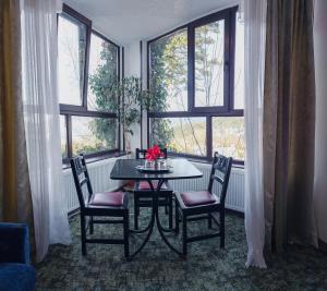 a dining room with a table and chairs and windows at Pensiune turistica Milcov-VLADET in Predeal