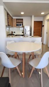 cocina con mesa blanca y 2 sillas en Caleta Design Puerto Madryn, en Puerto Madryn