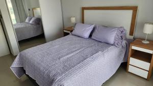 Un dormitorio con una cama grande con almohadas moradas. en Caleta Design Puerto Madryn, en Puerto Madryn