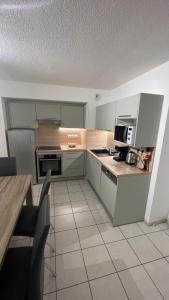 a kitchen with green cabinets and a table with chairs at Appartement 65m² idéalement placé pour 6 pers. in Brides-les-Bains