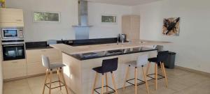 una cocina con encimera con taburetes alrededor en Villa de standing piscine chauffée vue mer Corse du sud, en Coti-Chiavari