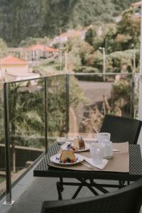 a table with two plates of food and cups on a balcony at Bela Vista House in Ponta Delgada