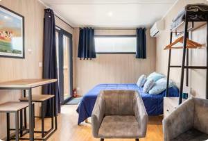 a bedroom with a blue bed and a chair at La chambre des oliviers in Aubais