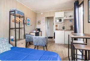 a bedroom with a blue bed and a kitchen at La chambre des oliviers in Aubais