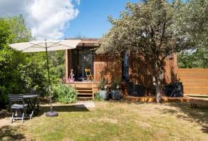 a house with a table and an umbrella in the yard at La chambre des oliviers in Aubais