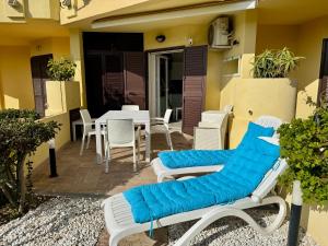patio z krzesłami i stołem z niebieską poduszką w obiekcie Appartamenti delfini terza spiaggia w mieście Golfo Aranci