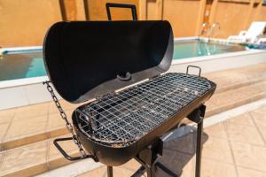 a black grill sitting next to a swimming pool at Queen Massarossa Pool Villa Pattaya-25 in Pattaya Central