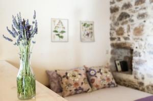 a vase of flowers sitting on a table with a couch at Orgon Farm Village Houses in Apóstoloi +26 photos