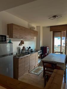 a kitchen with wooden cabinets and a table and a refrigerator at Fiocco Di Neve in Aprica
