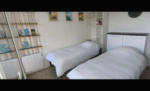 two beds in a room with white walls and shelves at Studio les mouettes in Mimizan-Plage