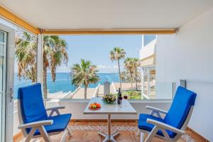 Un comedor con mesa y sillas y el océano. en Sunsuites Collection - Las Flores, en San Bartolomé