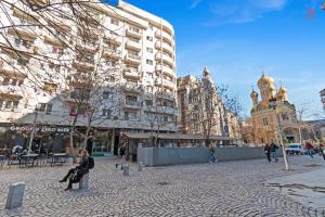 a woman is sitting on a street in a city at Charm Apartment - Old Town in Bucharest