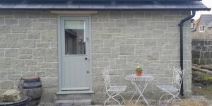a stone house with a white door and a table and chairs at Private Ensuite Room, Swallowcliffe in Swallowcliffe