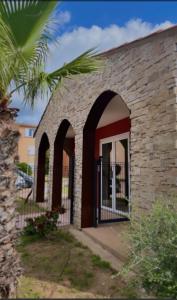 LecciにあるLes hameaux de Saint Cyprien - appartement avec jardin et piscineの煉瓦造りのアーチとヤシの木 +8枚の写真