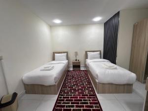two beds in a small room with a rug at Uncle Ali hotel in Wadi Musa