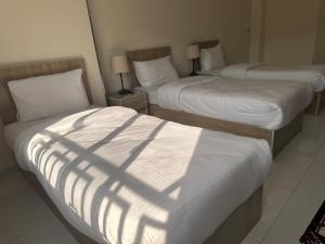 two beds in a hotel room with shadows on them at Uncle Ali hotel in Wadi Musa